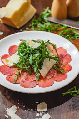 Beyaz tabakta roka ve parmesan peyniri ile et carpaccio. Yakın çekim