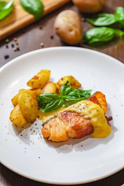 Pastırma ve patates dilimleri beyaz plaka üzerinde sarılı ızgara somon fileto. Yakın çekim