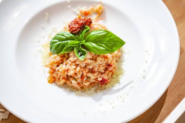 Kurutulmuş domatesli risotto ve beyaz tabakta kapari. Kapat.