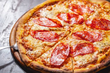İtalyan Pepperoni pizzası mozzarella peyniri ve ahşap tahtada salam. Kapat.