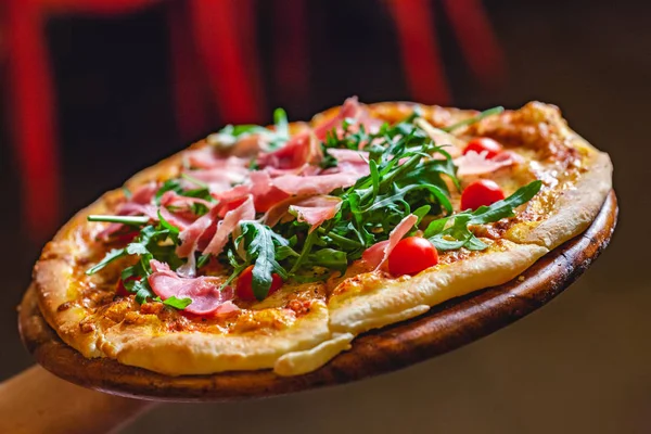İtalyan Pizza jambon (parma ham), roka (salata roket) ve kiraz domates ile tutarak Şef. Yakın çekim