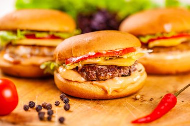 Dana pirzola, domates ve peynirle ahşap tahta üzerinde üç mini burgerler