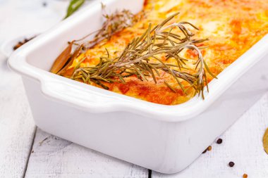 Ahşap rustik masa üzerinde beyaz güveç çanağı içinde Patates graten. Yakın çekim