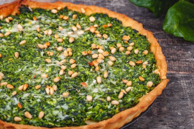 Ispanak, ricotta peyniri ve çam fıstığı ahşap rustik masa üzerinde tart. Yakın çekim