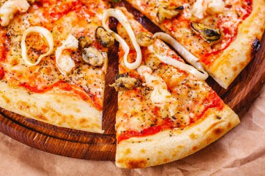 Tahta kesme tahtasının üzerinde deniz ürünleri ve mozzarella peynirli İtalyan pizzası. Kapat.