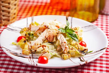 Tavuklu Sezar salatası ve beyaz tabakta pastırma. Kapat.