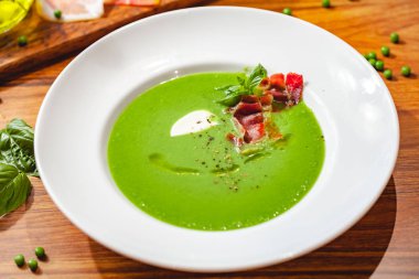 Beyaz tabakta pastırmalı yeşil bezelye kremalı çorba. Kapat.