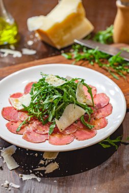Beyaz tabakta roka ve parmesan peyniri ile et carpaccio. Yakın çekim