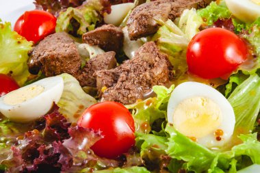 Beyaz plaka üzerinde tavuk karaciğeri, domates ve yumurta ile sıcak salata. Yakın çekim