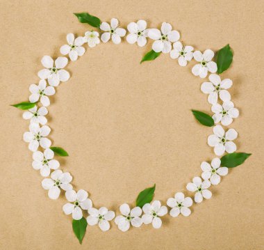 Yuvarlak kare çelenk beyaz bahar çiçekleri yapılmış ve yeşil kahverengi kağıt arka plan üzerinde bırakır. Üstten Görünüm. Düz yatıyordu.