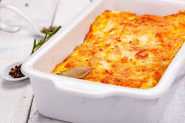 Ahşap rustik masa üzerinde beyaz güveç çanağı içinde Patates graten. Yakın çekim