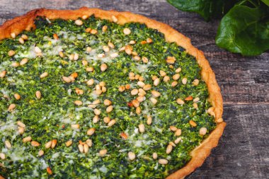 Ispanak, ricotta peyniri ve çam fıstığı ahşap rustik masa üzerinde tart. Yakın çekim