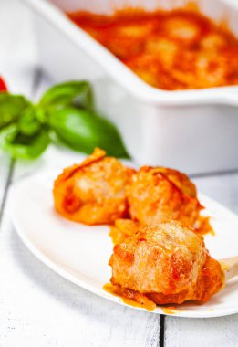 Beyaz tabakta domates ve ekşi krema soslu köfte. Yakın çekim