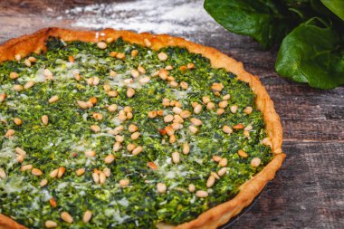 Ispanak, ricotta peyniri ve çam fıstığı ahşap rustik masa üzerinde tart. Yakın çekim