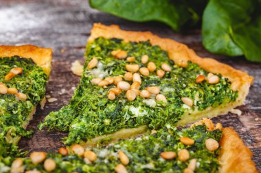 Ispanak, ricotta peyniri ve çam fıstığı ahşap rustik masa üzerinde tart. Yakın çekim