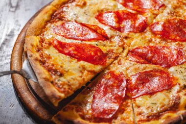 İtalyan Pepperoni pizzası mozzarella peyniri ve ahşap tahtada salam. Kapat.