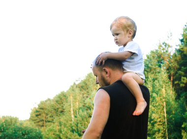 Küçük bir çocuk babasının omuz tırmandı ve orada oturur bir papağan gibi. Baba oğlu ile oynar, onu giyer, aptallar