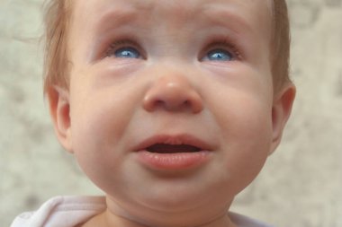 Üzgün, ağlayan çocuk dudaklarını cüzdanlar ve gözyaşları tutuyor. Portre bej tonlarında