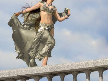 Bir kız oryantal dans için gümüş bir kostüm sonbahar güneş ışınlarının rüzgarda duruyor