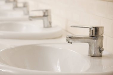 Birçok kapalı krom kaplama musluk bir umumi tuvalet üst üste stand. Oda temiz ve parlak.