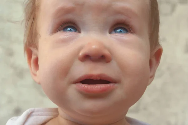 Üzgün, ağlayan çocuk dudaklarını cüzdanlar ve gözyaşları tutuyor. Portre bej tonlarında