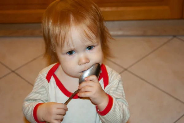 小女孩手里拿着勺子舔勺子 教孩子独立吃饭 — 图库照片