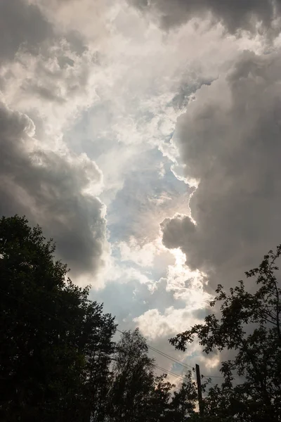 The encouraging clearance of rain clouds gives hope for the cessation of drizzling rain and good weather. The sun\'s rays make their way between the high cumulus clouds.