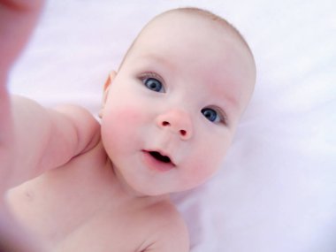 Küçük neşeli bebek kız bebek ve hava banyoları, daldırma cilt güneş alır. Bebek kızarıklık yanaklarda, soğuktan benzer vardır..