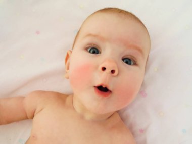 Küçük neşeli bebek kız bebek ve hava banyoları, daldırma cilt güneş alır. Bebek kızarıklık yanaklarda, soğuktan benzer vardır..
