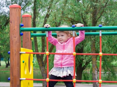 Merdivenler ve crossbars yerel park Bahçesi tırmanmak küçük bir kız öğrenir.