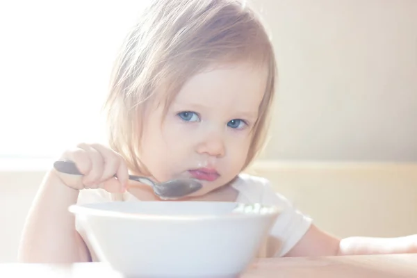 小毛茸茸的女婴与快乐独自拿着勺子 吃美味的食物从一个白色的盘子 — 图库照片