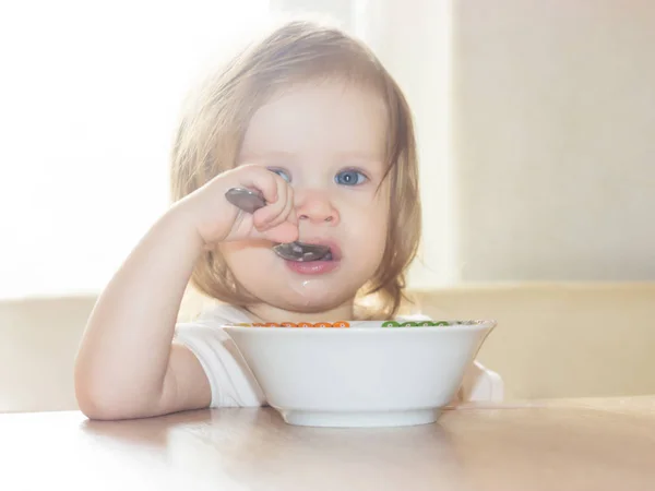 小毛茸茸的女婴与快乐独自拿着勺子 吃美味的食物从一个白色的盘子 — 图库照片