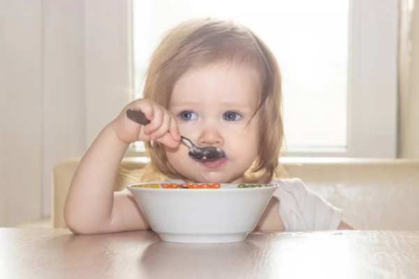 小毛茸茸的女婴与快乐独自拿着勺子 吃美味的食物从一个白色的盘子 — 图库照片