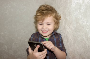 Küçük bir yürümeye başlayan çocuk elinde bir gadget tutar ve akıllı telefon ekranında tıklamalar. Bir çocuk onun ebeveynler Smartphone ile oynamak için izin verildi mutlu.