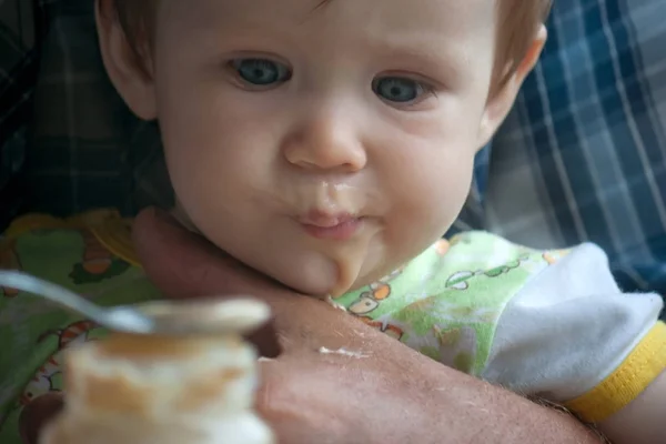 一个小女孩坐在她祖父的怀里 用勺子吃水果泥 在儿童中引入补充食物 大粗糙的手轻轻地支持婴儿 用勺子喂食 — 图库照片