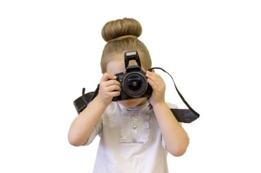 İş kıyafetleri giyen küçük bir kız, elinde bir refleks kamera tutuyor. Çocuk fotoğraf çekmek istiyor. Bebek fotoğraf çekmeyi öğrenir ve karmaşık tekniği inceler.