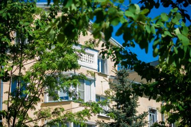 Taze yeşil ağaç tepelerinde Sovyet döneminde inşa edilmiş İmparatorluk tarzında neoklasik bina örneğinin yanında avlu kaplar.