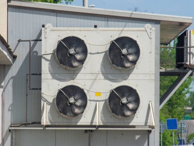 Endüstriyel bir binanın cephesine klimalardan harici bir fan ünitesi iliştirilmiştir. Binanın duvarında döner bıçaklar fabrika fanı.