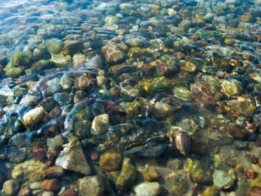 Berrak su altında küçük yuvarlak taşlar.