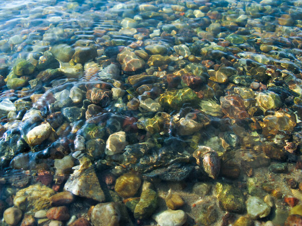 Маленькие круглые камни под чистой водой
.