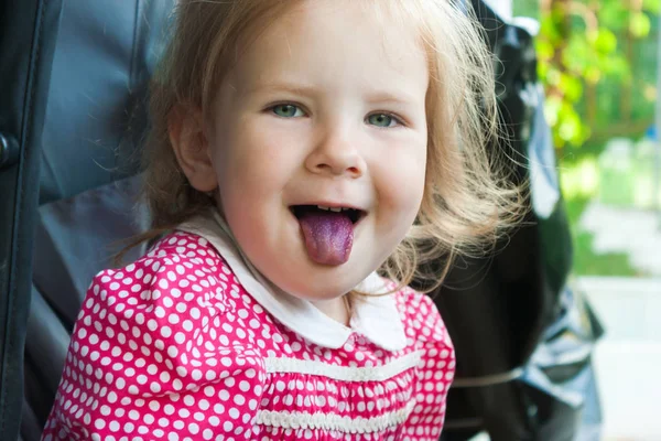 Маленька мила дівчинка показує язик чорниці . — стокове фото