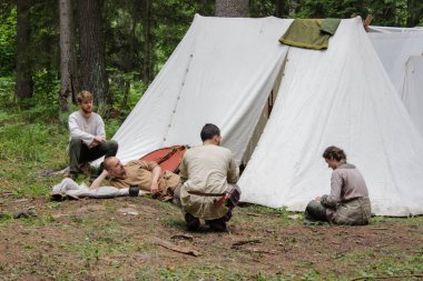 Grodek, Polonya - 13 Temmuz 2019. Erken Ortaçağ hayatında yetişkinler için bir oyun. Tarihi kostümlü insanlar çadırların yanında oturup rahatlarlar. Göçebeler ormanda durdu.