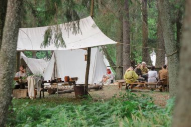 Grodek, Polonya - 13 Temmuz 2019. Erken Ortaçağ hayatında yetişkinler için bir oyun. Tarihi kostümlü insanlar çadırların yanında oturup rahatlarlar. Göçebeler ormanda durdu.