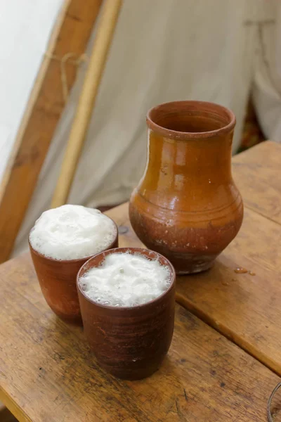 Seramik seramik kil sürahi ve iki kupa ahşap bir masa üzerinde durmak.