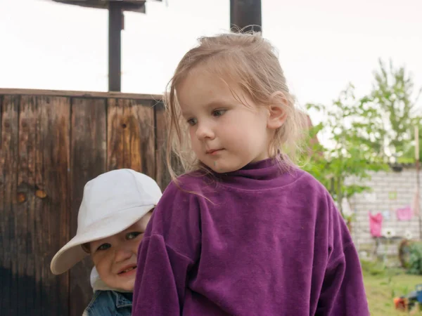 Der kleine Junge ist aufgebracht und hat Angst. Der jüngere Bruder versteckt sich hinter seiner Schwester auf der Suche nach Halt und Schutz. — Stockfoto