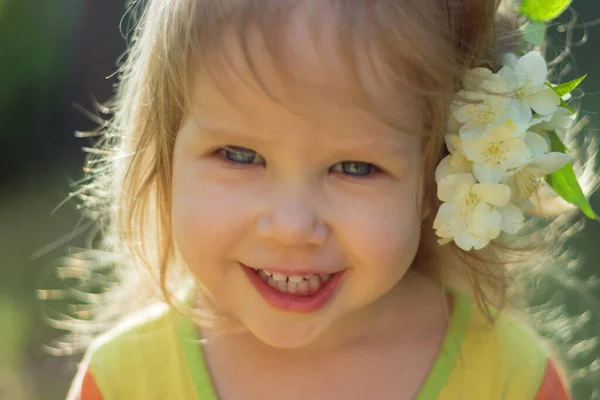 Portret van een klein schattig meisje met een jasmijnbloem in haar haar — Stockfoto