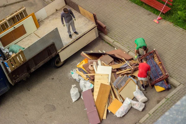 Рабочие грузят старую мебель в багажник грузовика для транспортировки — стоковое фото