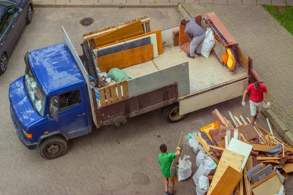 Arbeiter laden alte Möbel in den hinteren Teil eines Lastwagens, um sie zu transportieren — Stockfoto