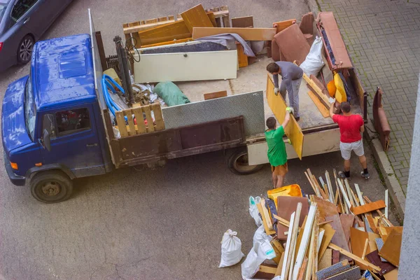 Рабочие грузят старую мебель в багажник грузовика для транспортировки — стоковое фото