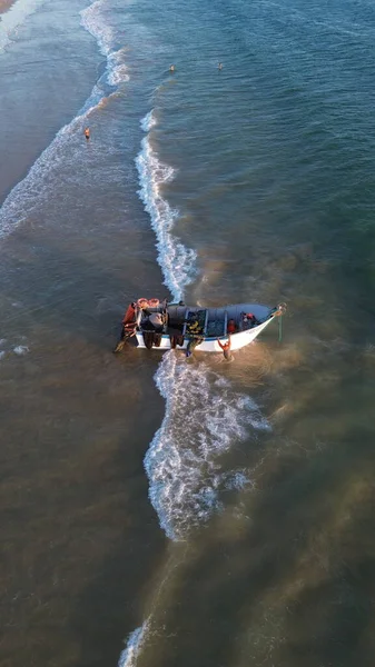 Costa da Caparica, Portekiz 22 Ağustos 2025: Balıkçıların teknelerini okyanus dalgalarına sürdükleri hava manzarası. Sahilde geleneksel balıkçılık sahnesi, takım çalışması ve deniz yaşamı yukarıdan ele geçirildi.